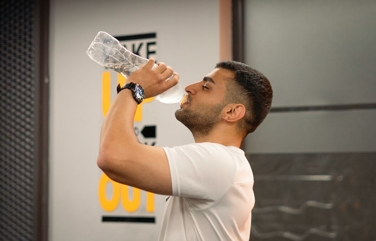 man drinking water from bottle in gym - water retention weight gain