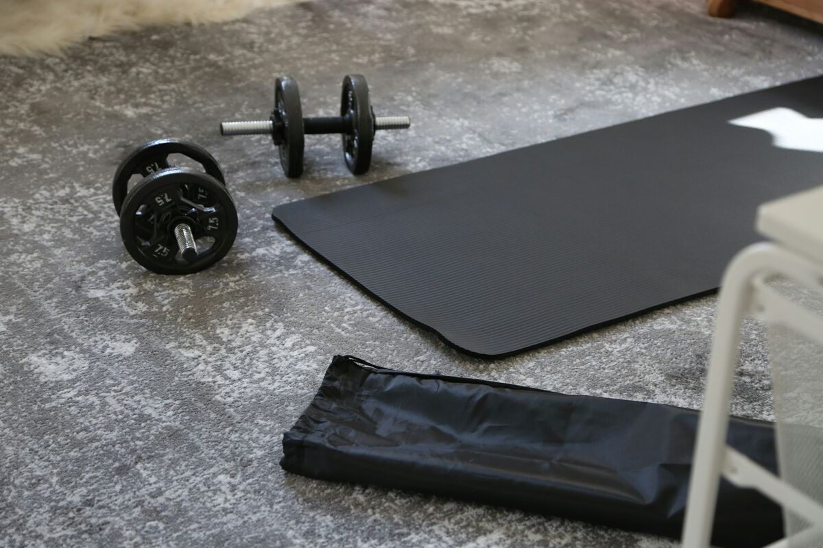Dumbbells and mat on gym floor for lunges - lower body hypertrophy workout