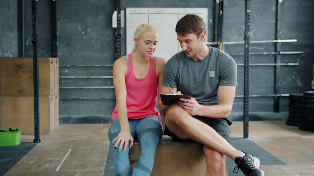 Man and woman using tablet in gym - workout tracking