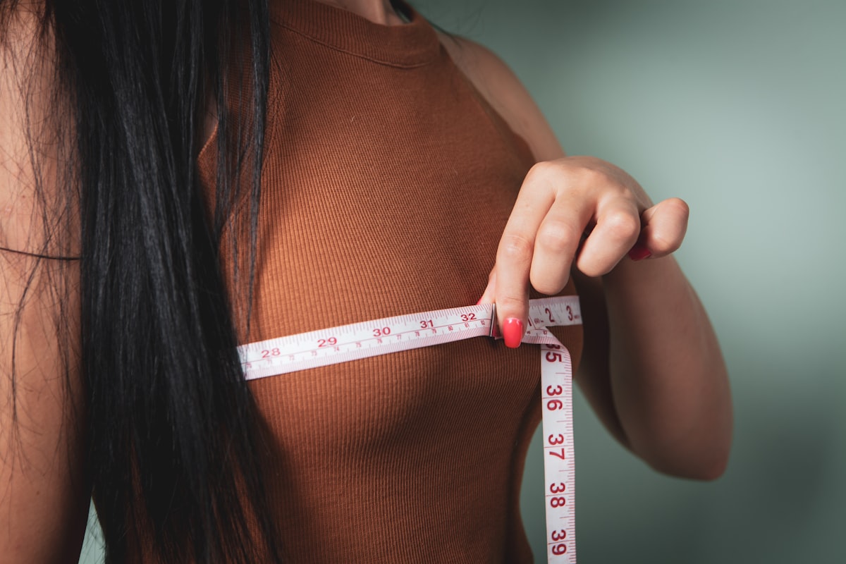 Woman measuring her waist with tape measure - spot reduction myth