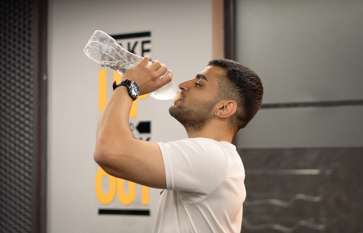 Man drinking water from bottle in gym for peak performance