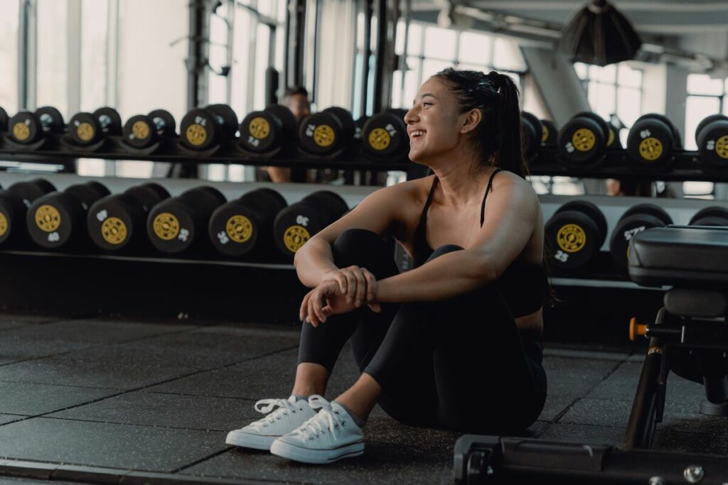 Woman sitting on the ground in a gym - no days off myth - fitness friday facts