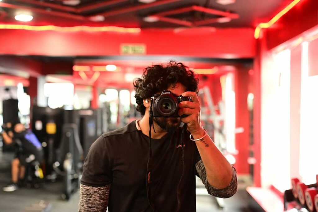 A person taking a progress photo in the gym mirror using a smartphone app