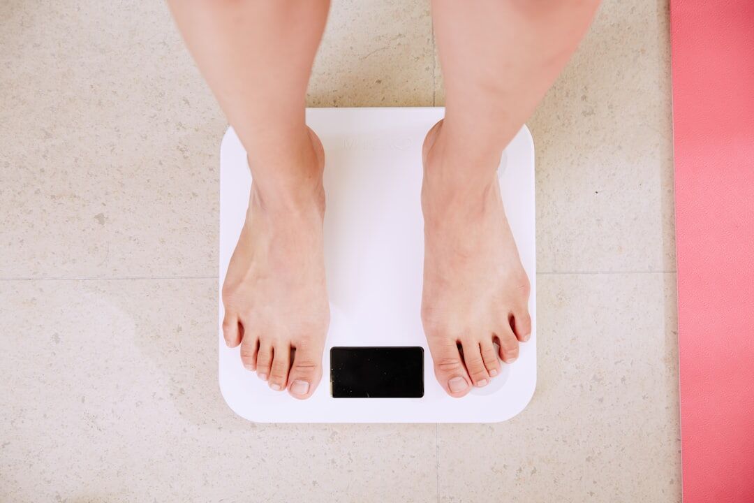 A person standing on a smart body composition scale measuring body weight and fat percentage