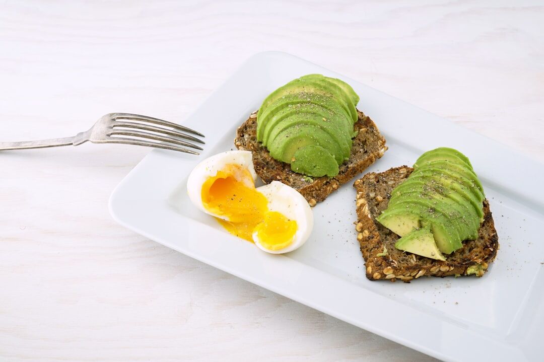 Avocado toast topped with soft boiled egg showing balanced macronutrients