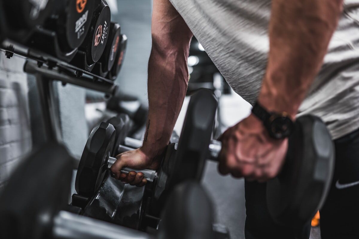 complete arm day workout - athlete performing close-up dumbbell curl showing bicep contraction