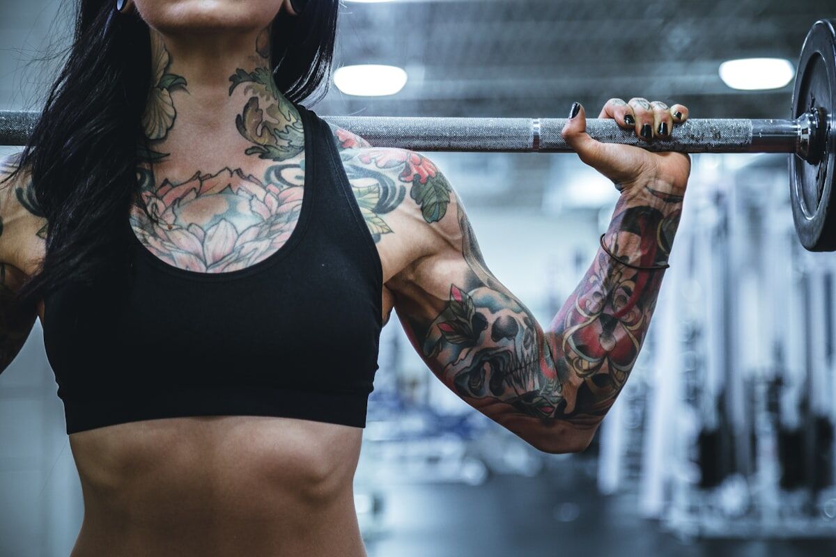 complete arm day workout - woman performing barbell bicep curls in the gym