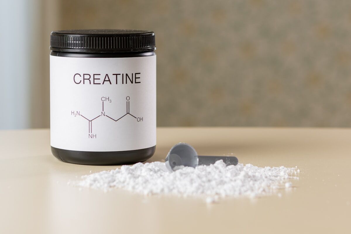creatine for muscle growth - a jar and scoop of creatine supplement powder