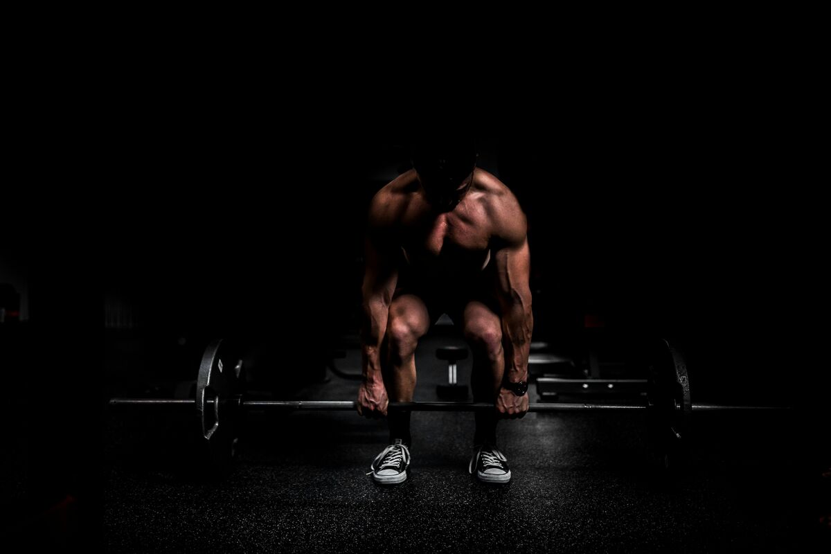 Athlete lifting heavy barbell in a gym - free weight lifting - fitness friday facts