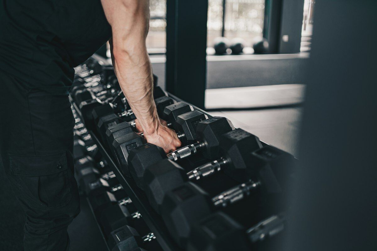 Man training with weights in gym - strength before cardio - fitness friday facts