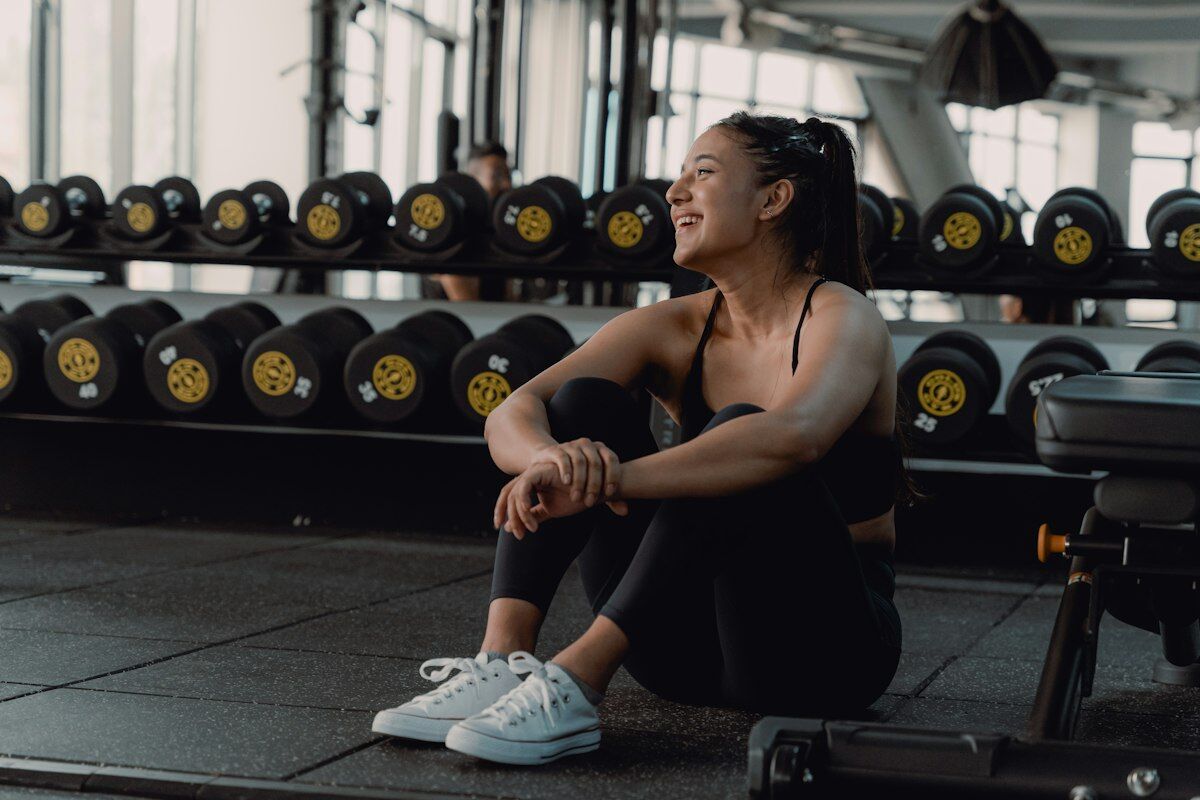 Woman resting between workout sets in gym - active recovery - fitness friday facts